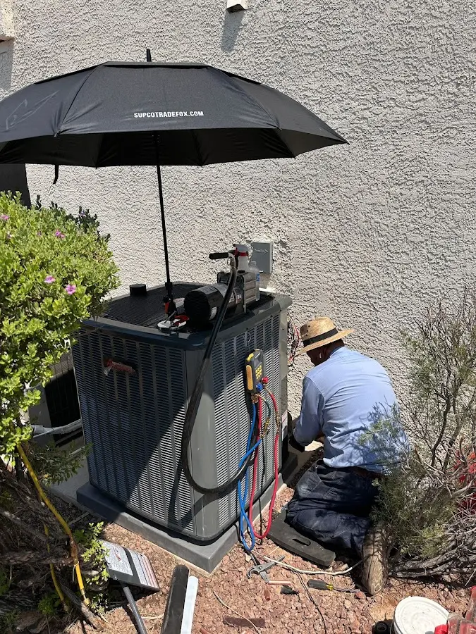 HVAC technician performing outdoor AC maintenance in East Alton